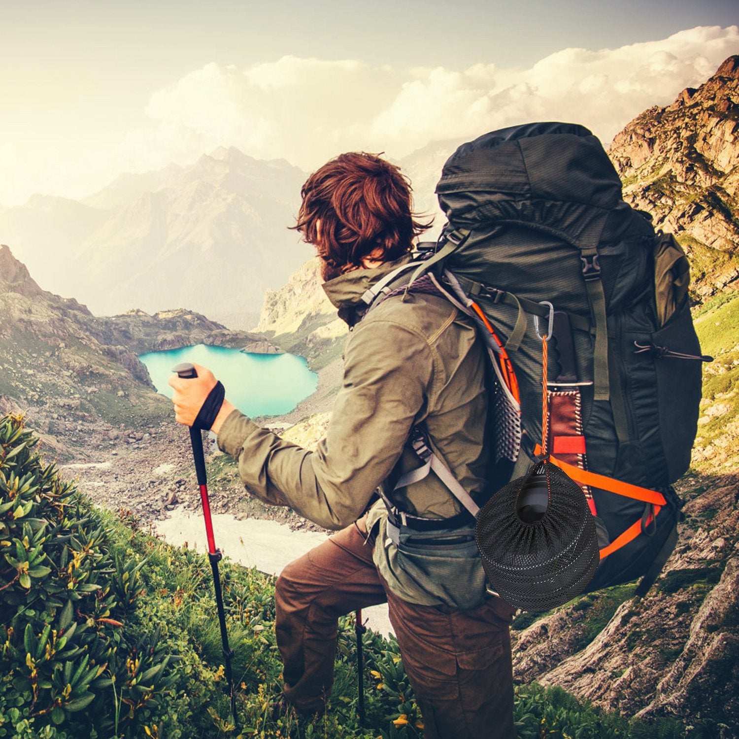 Hiker with a large backpack and trekking poles overlooking a scenic mountain landscape with a lake.
